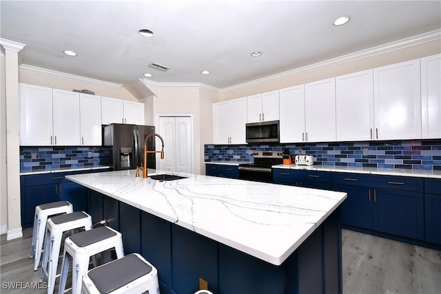 kitchen featuring white cabinetry, stainless steel appliances, and a center island with sink