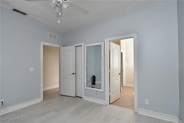 unfurnished bedroom featuring multiple closets, ceiling fan, and light hardwood / wood-style floors