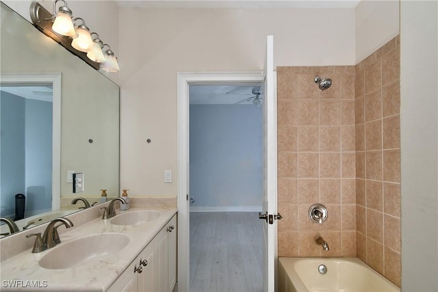 bathroom with ceiling fan, tiled shower / bath, vanity, and wood-type flooring