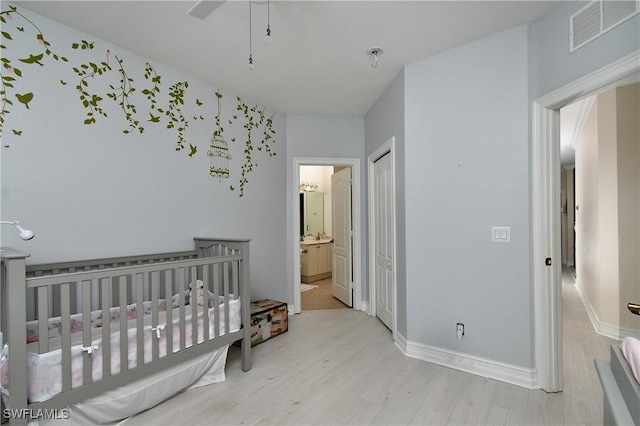 bedroom featuring a closet, light hardwood / wood-style floors, and ensuite bath