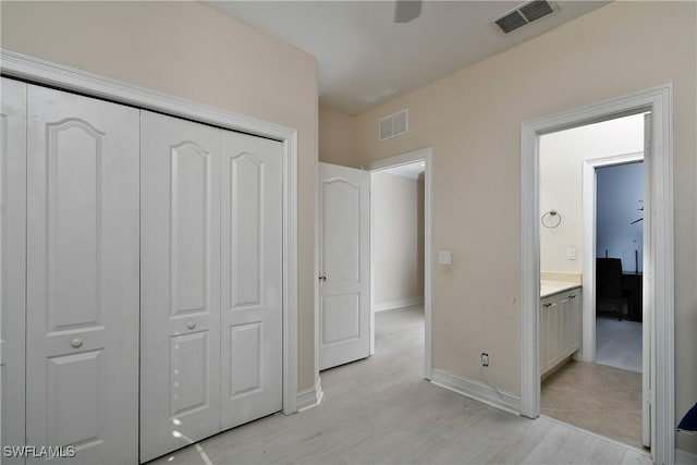 unfurnished bedroom with ensuite bath, light hardwood / wood-style flooring, and a closet