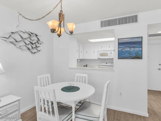 dining area with wood-type flooring and an inviting chandelier