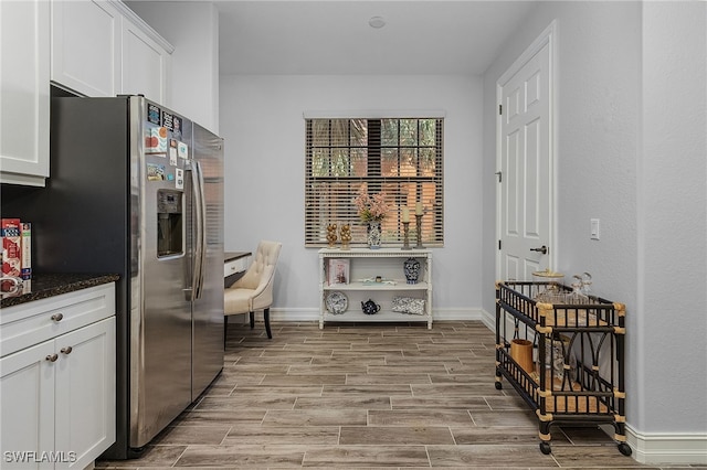 kitchen with white cabinetry, stainless steel fridge, and dark stone counters