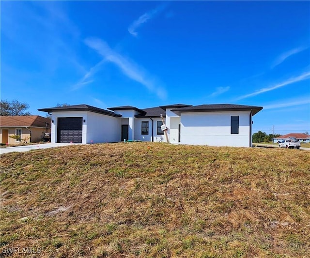 view of front facade featuring a garage, stucco siding, concrete driveway, and a front yard