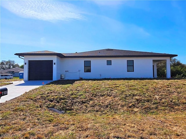 exterior space featuring a front lawn, driveway, an attached garage, and stucco siding