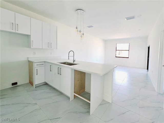 kitchen with pendant lighting, marble finish floor, light countertops, open floor plan, and a peninsula