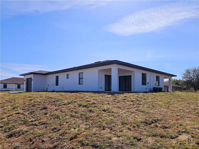 rear view of house featuring stucco siding and a yard