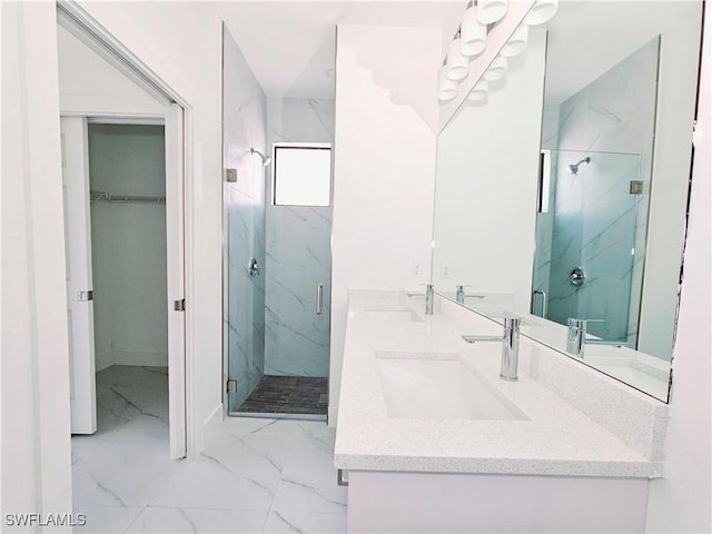 bathroom featuring marble finish floor, a spacious closet, a sink, and a marble finish shower