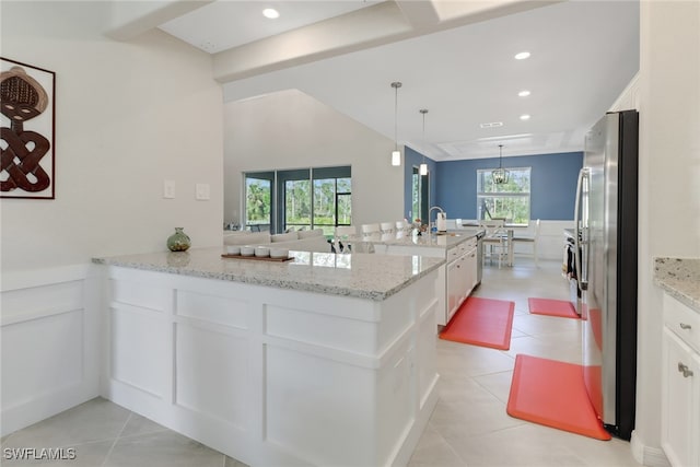 kitchen with decorative light fixtures, white cabinetry, light stone countertops, and kitchen peninsula