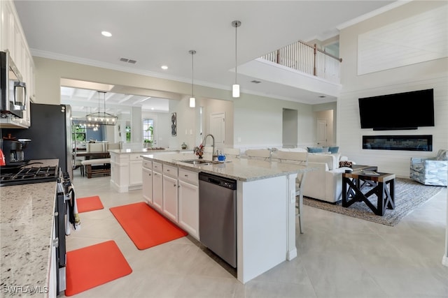 kitchen with white cabinetry, a center island with sink, decorative light fixtures, sink, and appliances with stainless steel finishes