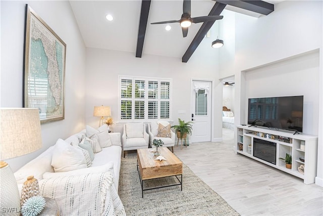 living room with ceiling fan, high vaulted ceiling, light wood-type flooring, and beam ceiling