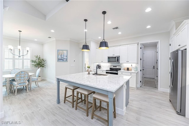 kitchen with a kitchen island with sink, hanging light fixtures, white cabinetry, and stainless steel appliances