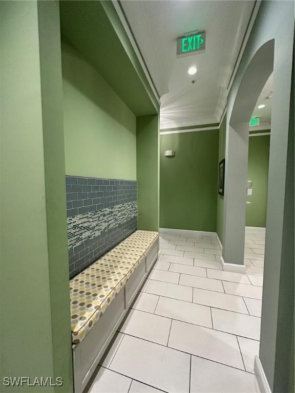 corridor featuring crown molding and light tile patterned floors