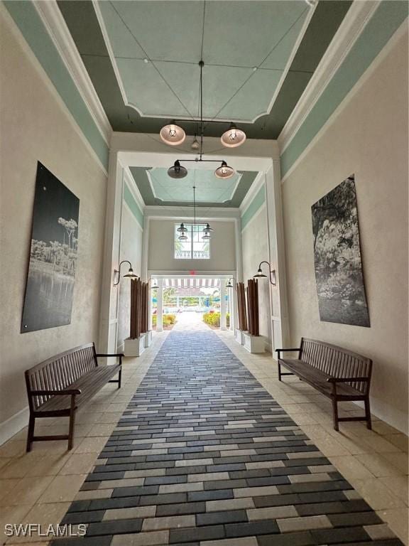 hallway with crown molding, a towering ceiling, and a tray ceiling