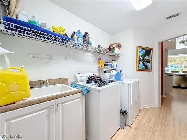 laundry room featuring cabinets, separate washer and dryer, sink, and light wood-type flooring