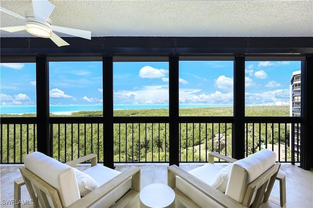 sunroom / solarium featuring a water view and ceiling fan