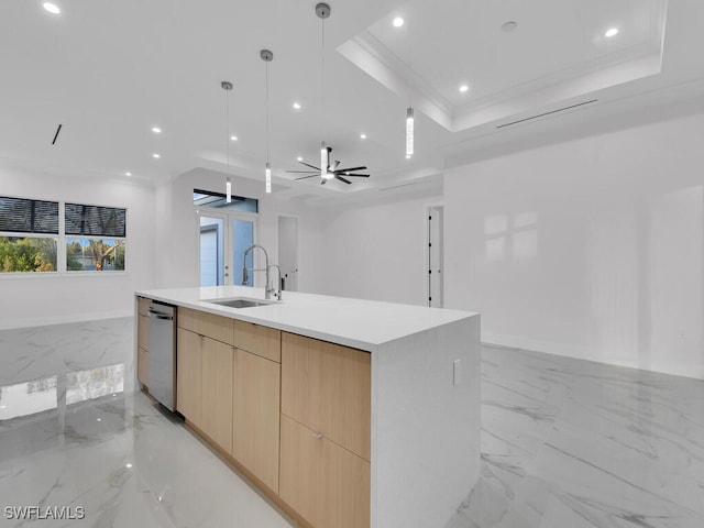 kitchen featuring a kitchen island with sink, stainless steel dishwasher, light brown cabinets, and a tray ceiling