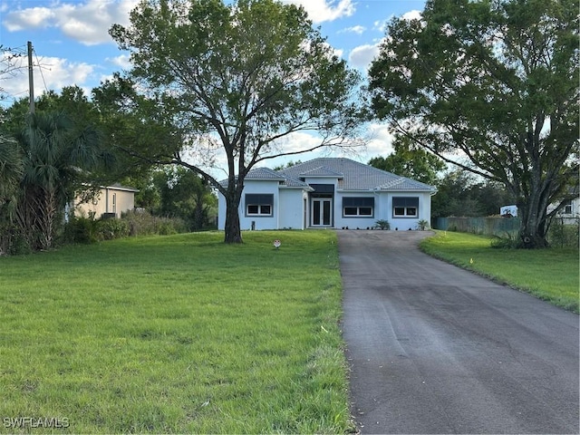 view of front of house featuring aphalt driveway, fence, a front lawn, and stucco siding