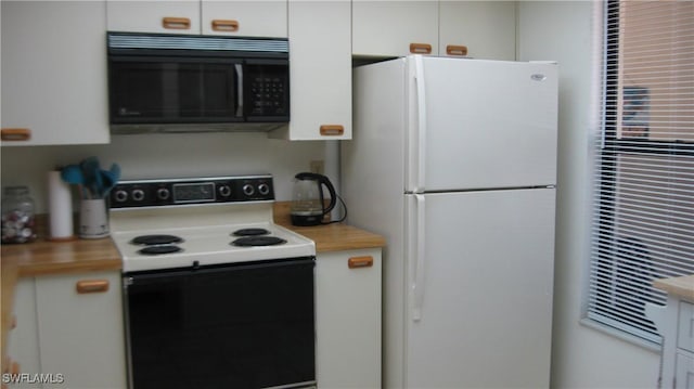 kitchen featuring electric range, white cabinets, and white refrigerator