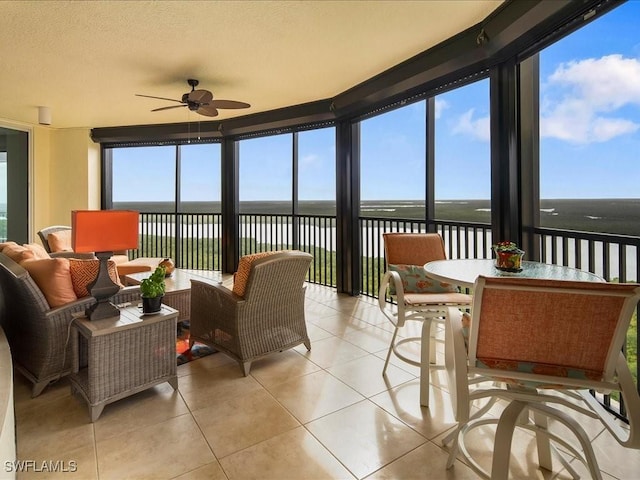 sunroom / solarium with a water view, ceiling fan, and plenty of natural light