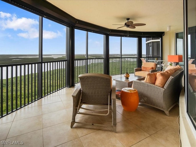 sunroom featuring a water view, ceiling fan, and a healthy amount of sunlight