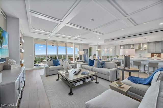 living room with an inviting chandelier, floor to ceiling windows, coffered ceiling, and light hardwood / wood-style floors