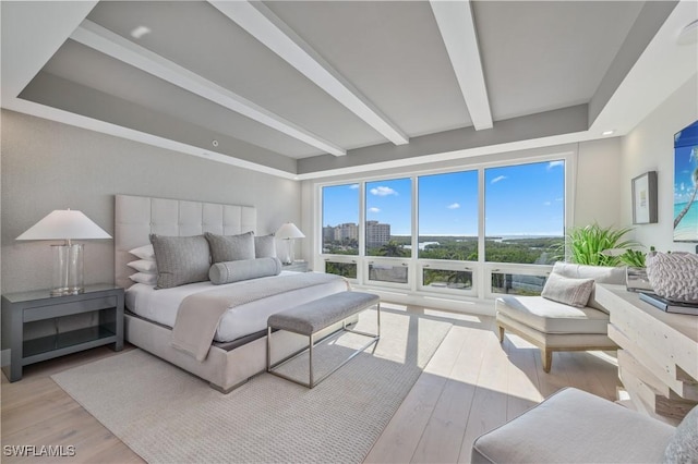 bedroom with light hardwood / wood-style floors and beamed ceiling