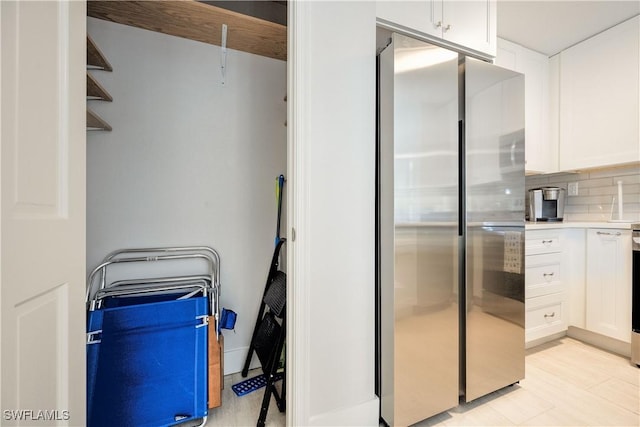 kitchen with white cabinetry, stainless steel fridge, and tasteful backsplash