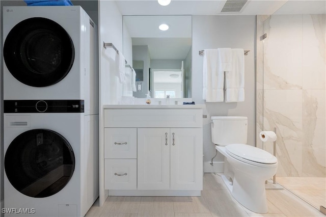 bathroom with vanity, stacked washer / drying machine, toilet, and walk in shower