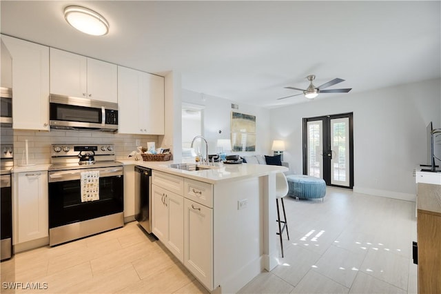 kitchen featuring white cabinetry, stainless steel appliances, kitchen peninsula, and sink