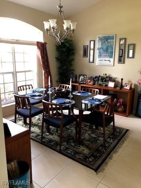 tiled dining area featuring vaulted ceiling and a chandelier