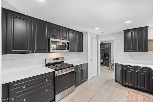 kitchen with appliances with stainless steel finishes, light tile patterned floors, and decorative backsplash