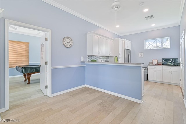 kitchen featuring white cabinetry, decorative light fixtures, stainless steel refrigerator, and kitchen peninsula