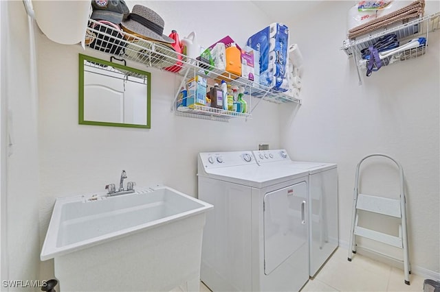 clothes washing area with sink, washing machine and clothes dryer, and light tile patterned flooring