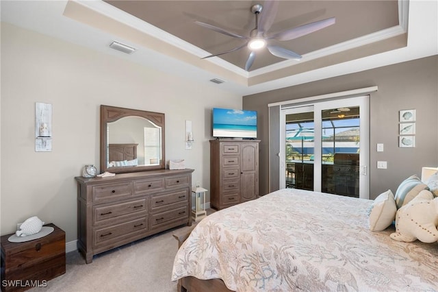 bedroom featuring visible vents, light carpet, a tray ceiling, and access to outside
