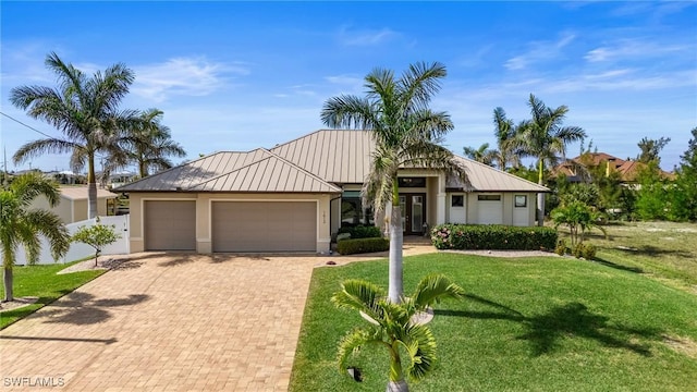 view of front of property with stucco siding, decorative driveway, metal roof, a front yard, and a garage