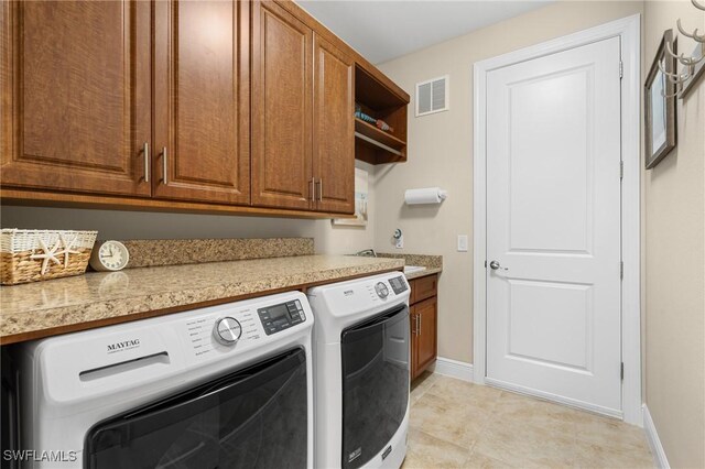 clothes washing area featuring separate washer and dryer, baseboards, cabinet space, and visible vents