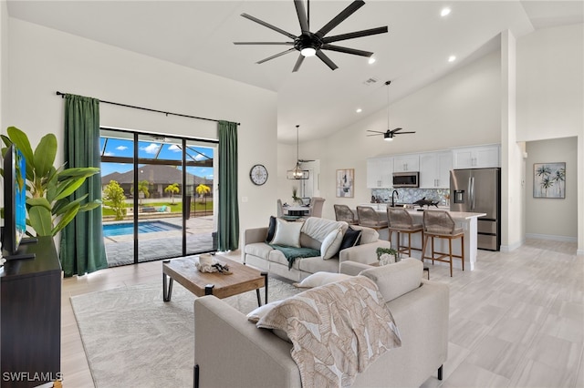 living room featuring ceiling fan, sink, and high vaulted ceiling