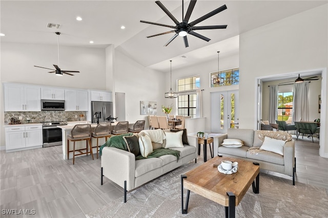 living room with high vaulted ceiling, ceiling fan, and french doors