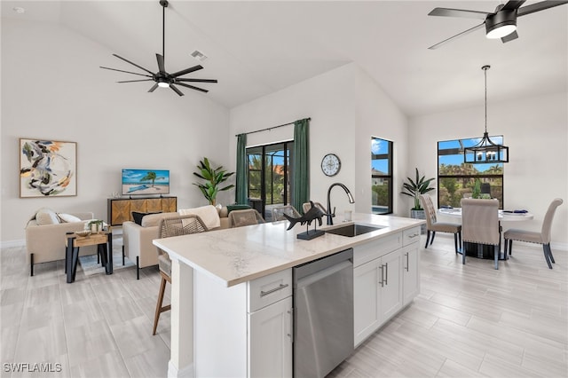 kitchen with sink, a kitchen island with sink, light stone counters, white cabinets, and stainless steel dishwasher