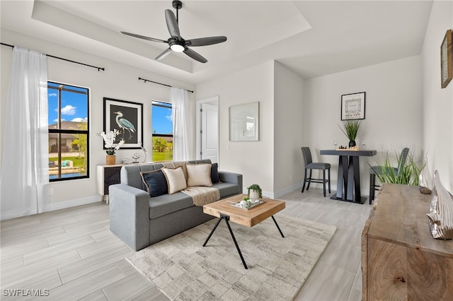 living room featuring ceiling fan and a tray ceiling