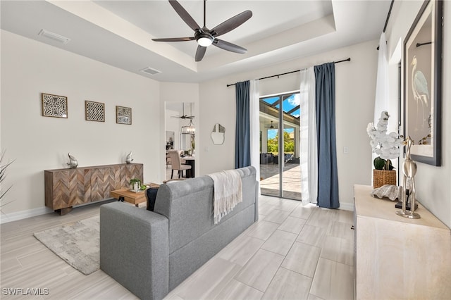 living room with ceiling fan and a raised ceiling