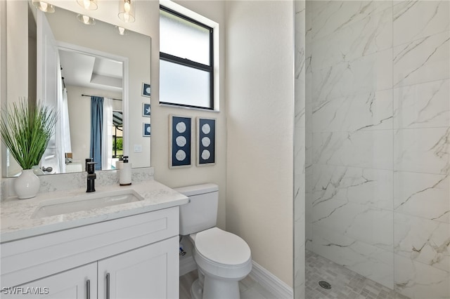 bathroom with vanity, toilet, and tiled shower