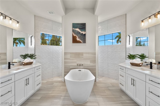 bathroom featuring tile walls, a tub to relax in, and vanity