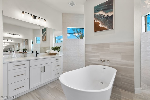 bathroom featuring tile walls, vanity, and a tub