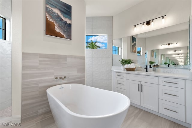 bathroom featuring tile walls, a bath, and vanity