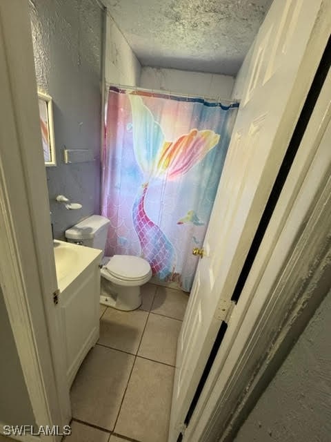 bathroom featuring tile patterned flooring, vanity, a textured ceiling, a shower with curtain, and toilet