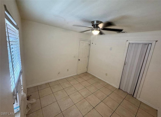 tiled spare room with ceiling fan