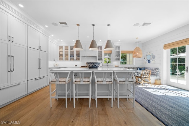 kitchen with a center island, pendant lighting, a breakfast bar, and white cabinets