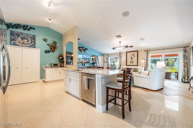 kitchen featuring an island with sink, sink, white cabinets, stainless steel appliances, and light stone countertops